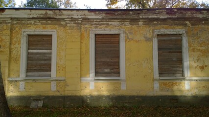 Old abandoned house in disrepair. Windows are filled with wooden planks instead of glass. Poverty, devastation, economic, financial and housing development crisis.  Loneliness, sadness and despondency