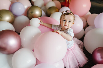 Fototapeta na wymiar Cute baby girl 1 year play with colorful balloons in the studio. Isolated. Birthday party. Celebration. Happy birthday baby. Play room in home.