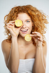 Happy smiling red hair woman holding lemon slices in hand