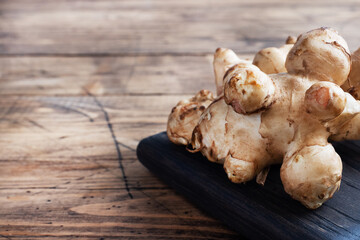 Raw Jerusalem artichoke, topinambur tubers on a rustic wooden background. Copy space.