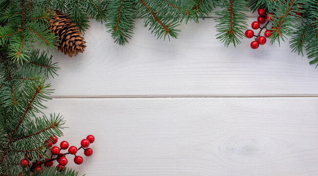 Christmas tree branches with pinecone and red berries on white wooden background and copy space for your text. Flat lay
