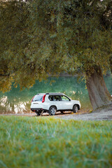 Fototapeta premium view of suv car at river beach on sunset