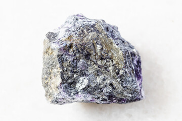 closeup of sample of natural mineral from geological collection - rough Stibnite (Antimonite) ore on white marble background from Ukraine