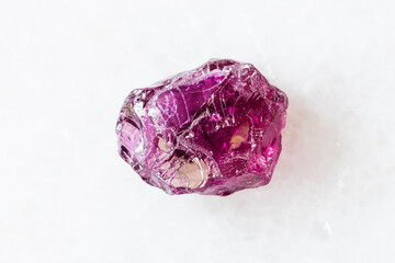 Fototapeta premium closeup of sample of natural mineral from geological collection - rough Rhodolite (pyrope garnet) crystal on white marble background from Lokirima, Lodwar, Turkana dist, Riffvalley prov, Kenya