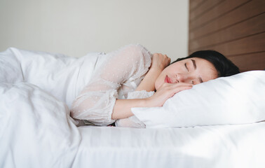 Fototapeta na wymiar Young beautiful Asian woman sleeping on bed in the morning