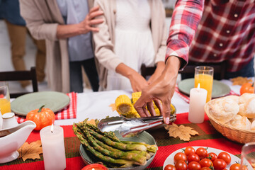 Cropped view of african american woman holding tweezers near food during thanksgiving celebration