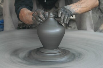 Potter modeling ceramic pot from clay on a potter's wheel