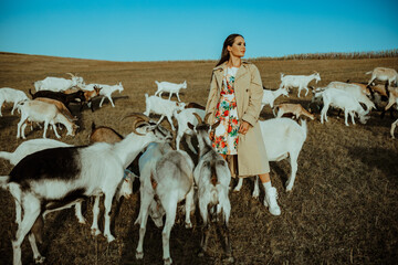 Shepherdess stands in a pasture among goats.