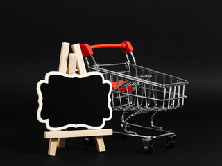 A frame on a stand and shopping cart on a black background, a blank for the design, concept. Copy...
