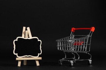 A frame on a stand and shopping cart on a black background, a blank for the design, concept. Copy...