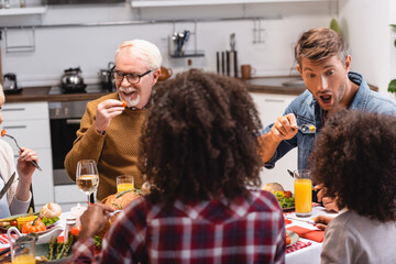 Selective focus of multiethnic family eating together during thanksgiving dinner