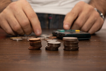 Selective focus shot of a stack of coins with a man counting money