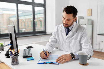 healthcare, medicine and people concept - male doctor with clipboard at hospital