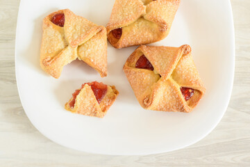 Homemade cookies with jam on a white plate. Delicious biscuits broken into pieces. Selective focus, blurred background.