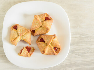 Homemade cookies with jam on a white plate. Delicious biscuits broken into pieces. Selective focus, blurred background.