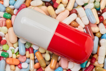 Big pill lies on many colorful medicines drugs