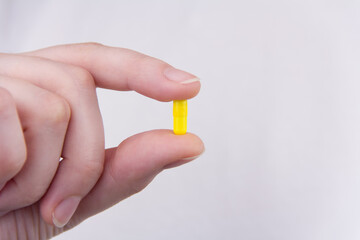 yellow pill capsule in a female hand
