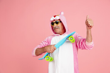 Skater in cool eyewear, thumb up. Portrait of senior hipster man in stylish attire isolated on pink...