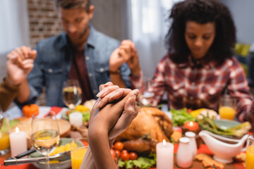 selective focus of multiethnic family with closed eyes holding hands on thanksgiving