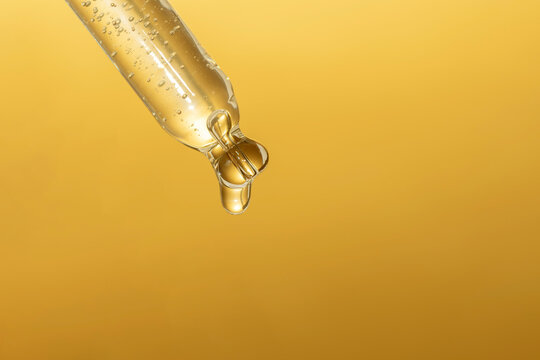 macro of pipette with liquid and drop on gold background