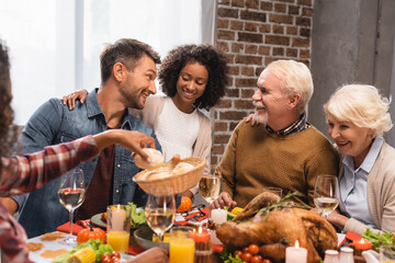 selective focus of african american girl taking bun near joyful family on thanksgiving