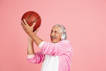Playing basketball with headphones. Portrait of senior hipster man in stylish attire isolated on...