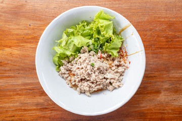 Thai Spicy Minced Pork with Egg Noodles served on a rustic wooden table.