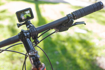 Action camera with the included screen mounted on the handlebar of a bicycle in the park