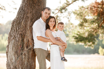 dad, mom hugging son outdoors in the park. The concept of summer holiday. Mother's, father's, baby's day. Family spending time together on nature. Family look. selective focus