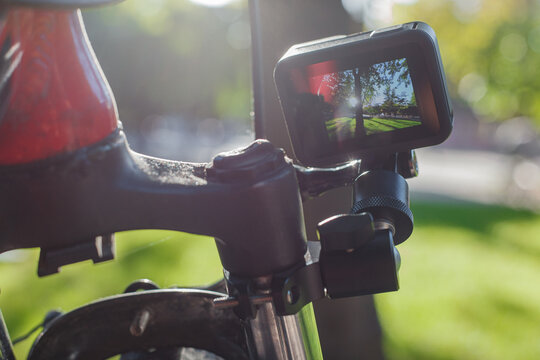Action camera with a screen on, mounted next to a mountain bike wheel