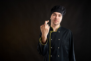 Young male dressed in a black chef suit showing good luck