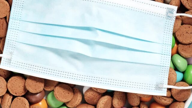 Disposable protective medical face mask with traditional dutch cookies kruidnoten. Dutch holiday Sinterklaas Saint Nicholas day during covid-19 pandemic in the Netherlands