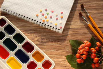 Paints with a Notepad on a wooden background.