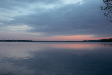 The landscape of the lake shore in Russia against the background of pink twilight, sunset. Large reservoir.