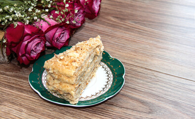 Layered cake with custard cream on the background of a bouquet of flowers.