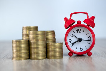 A red alarm clock and a pile of coins Concept of time and financial risk Business investments should be timely. Accounting and marketing.