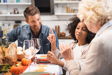 selective focus of african american girl showing idea gesture while celebrating thanksgiving with family