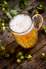 Beer mug with green hops and on a wooden table