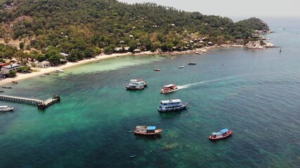 Boats in calm sea in port. Drone view of fishing and dive boats floating on tranquil surface of blue sea in harbor of tropical exotic paradise Koh Tao Island on sunny day in Thailand