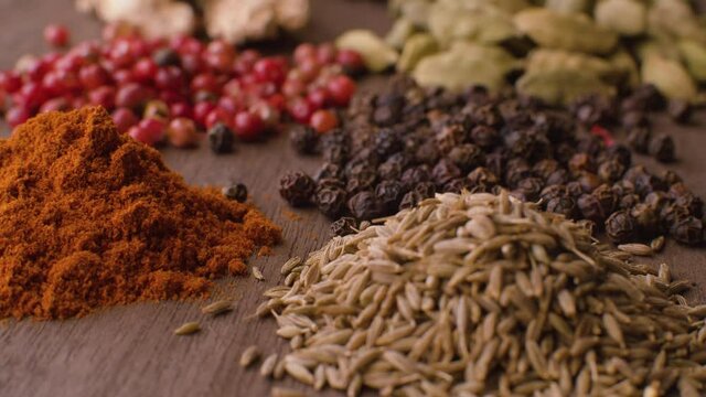 Macro shot indian spices on the table. Pepper, cardamom, turmeric, cumin seeds, ginger. Extreme close up, camera slowly moving on slider