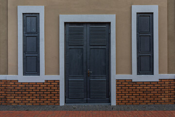 Wall with wooden doors and closed windows.
