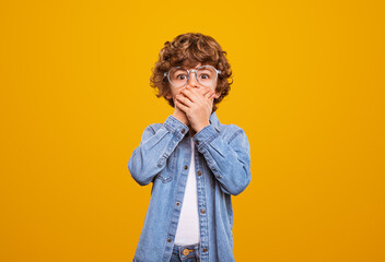 Amazed little boy covering mouth
