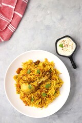 Chicken Biryani/murg Pulao.  Garnished with fried onion & chopped coriander. Biryani served with raita is a famous Spicy non vegetarian dish of India. Along with copy space.