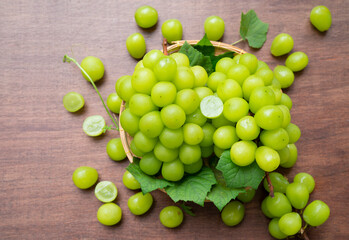 Green grape in Bamboo basket on wooden table in garden, Shine Muscat Grape with leaves in wooden background