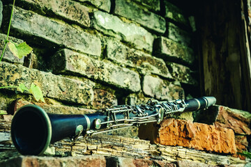 Old and dirty magic clarinet on a background of a beautiful old broken brick wall as symbol of...