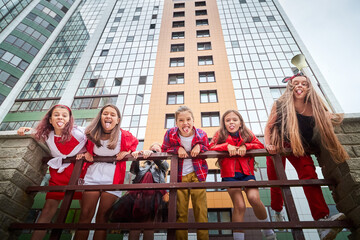 Group of fun children in stylish clothes near big modern house in the city