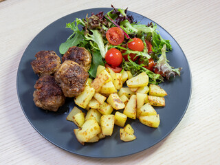 A plate of beef rissoles, roasted potato, and green salad.