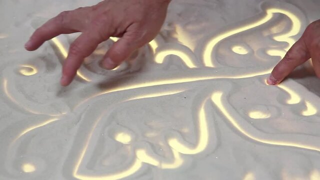The hands of an elderly woman draw on the sand butterfly. Psychological help