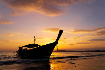 Traditional long-tail boat on the beach in Thailand at sunset