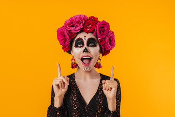 Photo of excited girl in halloween makeup pointing fingers upward